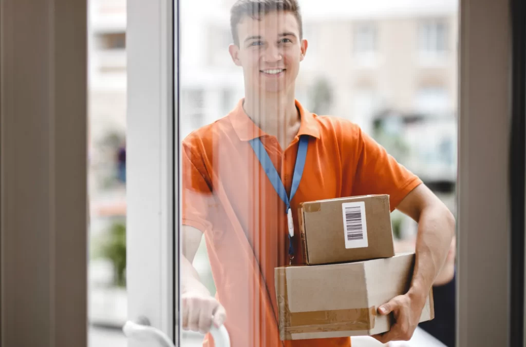 delivery person holding boxes arriving at door utc